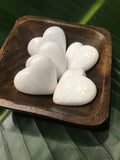 a wooden square bowl filled with white crystal scolecite hearts