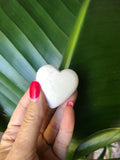 white scolecite crystal heart held in front of a green leaf
