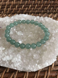 light green aventurine crystal bead bracelet on a white apophyllite crystal on a wicker tray