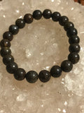dark brown bead bronzite crystal stretch bracelet on a white apophyllite crystal