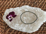 pyrite crystal stretch bracelet by a maroon orchid flower on a white apophyllite crystal on a wicker tray