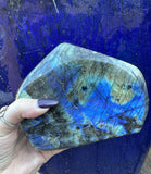 bright blue and green labradorite in front of a blue pot background