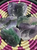 several rainbow fluorite heart shaped crystal dishes in a woven pink, black and white bowl