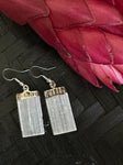 selenite earrings on a black background with a red flower