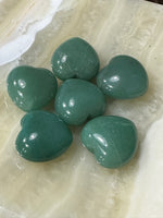 several small green aventurine crystal hearts on a white plate