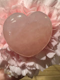 a close up of a pink rose quartz crystal heart in the middle of a light pink carnation