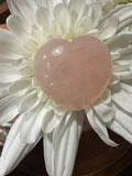 a light pink rose quartz crystal heart in the middle of a white flower