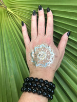 three 10 mm bead black tourmaline crystal stretch bracelet on a woman's arm with gold press on tattoo, black nails against a green palm leaf
