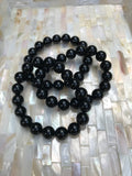 three 10 mm bead black tourmaline crystal stretch bracelets on a white shell like tray