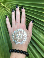 10 mm bead black tourmaline crystal stretch bracelet on a woman's arm with a gold tattoo and black nails against a green palm leaf