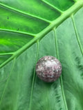 lepidolite crystal sphere on green leaf