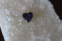 a raw heart shaped amethyst gold plated pendant on a white apophyllite crystal