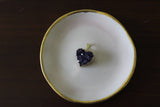 a purple raw heart shaped amethyst that is gold plated on a pink plate with gold trim on a brown background