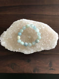 a light blue aquamarine crystal bracelet on a white apophyllite on a wooden table