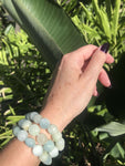 three aquamarine crystal green bracelets on a woman's arm against greenery