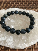 blue tigers eye crystal bracelet on a white apophyllite crystal on a wicker tray