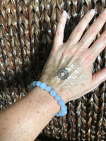 light blue chalcedony crystal bead bracelet on a woman's arm against a woven chair