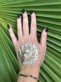 a mixed tourmaline faceted bead crystal bracelet on a woman's arm with a gold tattoo black nails against a green palm leaf