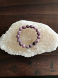 light purple lepidolite bracelet on a white apophyllite on a wood table