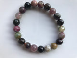 large bead size mixed tourmaline - purple pink gray green beads against a white background