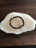 tiger's eye multi-color crystal stretch  bead bracelet on a white apophyllite crystal against a dark brown wood backgroun
