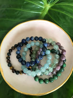 a pink tray with crystal braceletss - tiger's eye multi-color, sodalite, aquamarine, prehnite, lepidolite, ruby zoisite crystal stretch bracelets