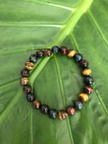 tiger's eye multi-color crystal stretch bead bracelet against a green elephant ear leaf