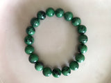 a green and purple ruby zoisite crystal bracelet on a white backgroun