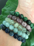 a woman's wrist showing sodalite, aquamarine, prehnite, lepidoliate and ruby zoisite crystal stretch bracelets 
