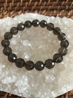 brown smoky quartz crystal stretch bracelet laying on top of white apophyllite on a wicker tray