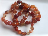 three orange tumbled carnelian crystal  bracelets on a white background