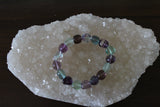 a tumbled fluorite crystal bracelet with green purple and blue beads on a white apophyllite crystal
