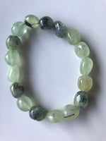 a light and dark green tumbled prehnite crystal stretch bracelet laying on a white backgroun