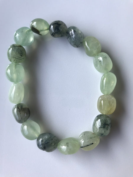 a light and dark green tumbled prehnite crystal stretch bracelet laying on a white backgroun